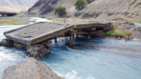 A broken bridge over a river with the blue water.の写真素材