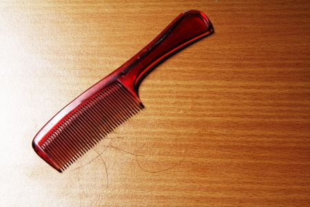 hair on a comb on wooden floor の写真素材