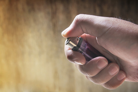 male hand holding a purple lightersの写真素材