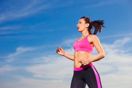 young woman running on blue sky with clouds backgroundの写真素材