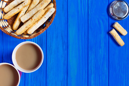 Two cups of cappuccino and italian bread sticks grissini served in rustic basket on blue wooden table, copy-space. Breakfast in cafeの写真素材