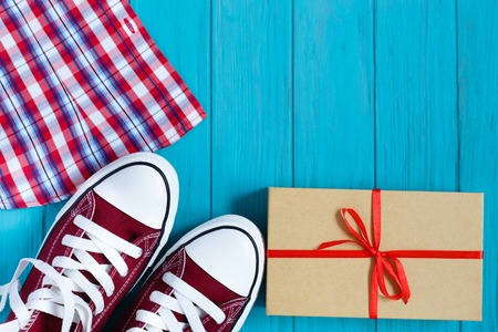 Burgundy sneakers, checkered shirt and gift box on bright turquoise background, free space for advertisement or text. Youth, dating, romantic, teenage, lifestyle conceptの写真素材