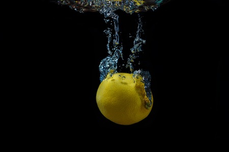 Lemon with water splash on a black backgroundの写真素材