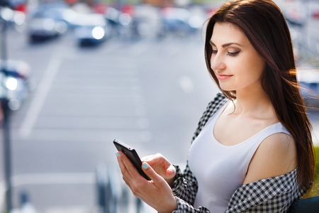 Young pretty stylish woman typing write message on smart phone iの写真素材