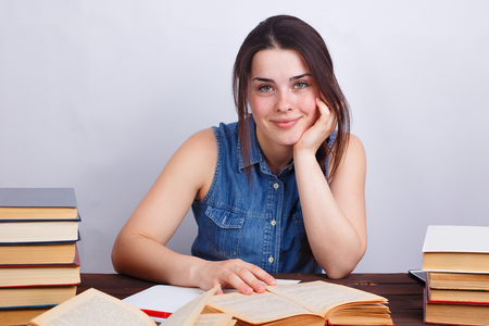 Portrait of young student girl sitting at desk and smilingの写真素材
