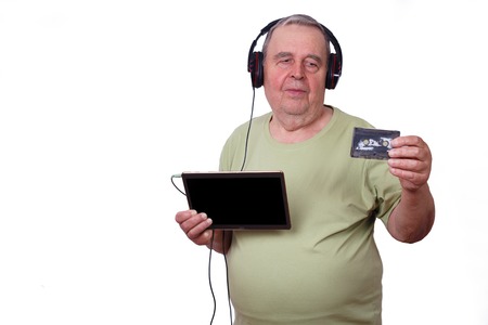 Portrait of old man listening to music in earphones using a tablの写真素材