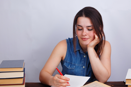 Portrait of young smiling student girl writing text to notebookの写真素材