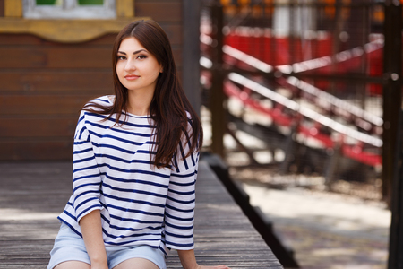 Young beautiful long-haired girl sitting outdoors. City walk, yoの写真素材