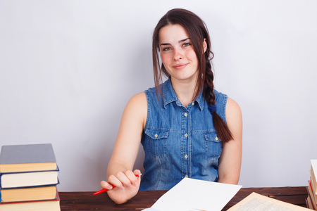 Young smiling student woman sitting at the table with empty papeの写真素材