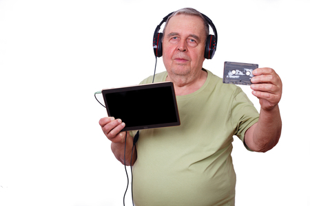 Portrait of old man listening to music in earphones using a tablの写真素材