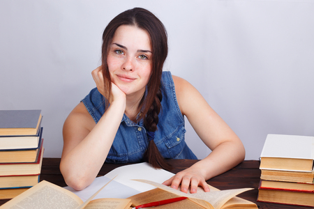Young smiling student woman sitting at the table with empty papeの写真素材