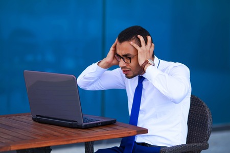 Young stressed business man manager with laptop sitting at table in coffee shop- business, people, paperwork and deadline conceptの写真素材