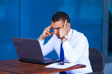 Paperwork, deadline concept. Stressed tired business man manager with laptop and papers sitting at table.の写真素材