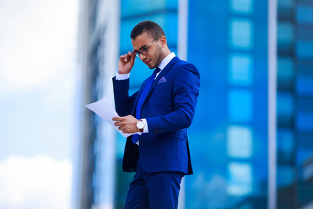 Happy business man reading papers near officeの写真素材