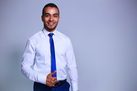 Portrait of confident young businessman standing on grey background. Business, people and office conceptの写真素材