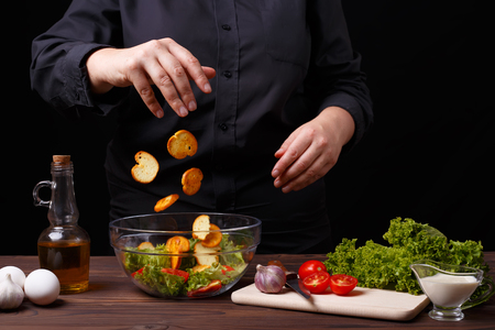 Chef dropping croutons to a bowl with caesar salad, cooking procの写真素材