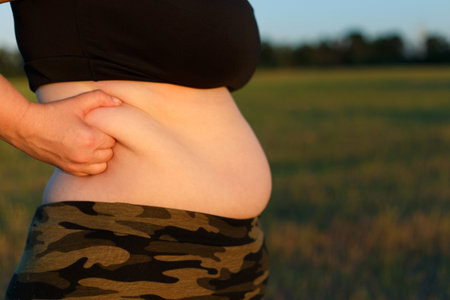 Overweight fat woman in camouflage pants standing outdoors  showの写真素材