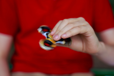 Hands of unknown boy playing with fidget spinner, close up. Trenの写真素材
