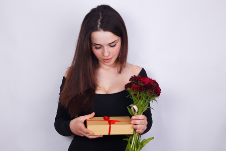 Young beautiful smiling woman with carnations and gift box in haの写真素材