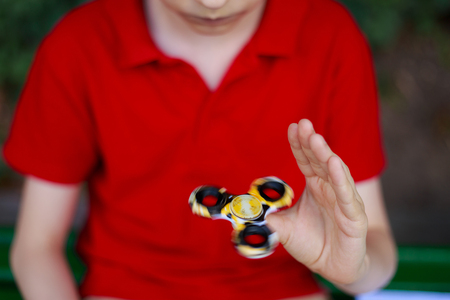 Hands of unknown boy playing with fidget spinner, close up. Trenの写真素材
