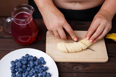 Overweight fat woman slicing a banana for fruit plate. Juicy tasの写真素材