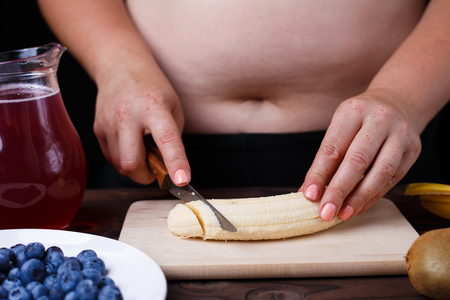 Overweight fat woman slicing a banana for fruit plate. Juicy tasの写真素材