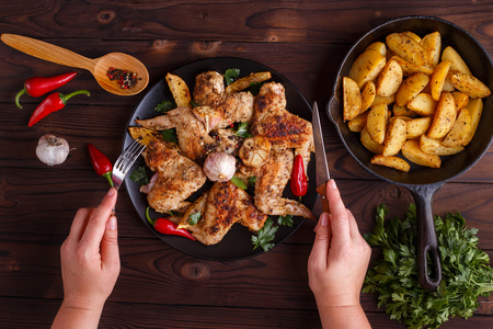 Woman hands tasting grilled chicken wings. Hot fresh appetizingの写真素材