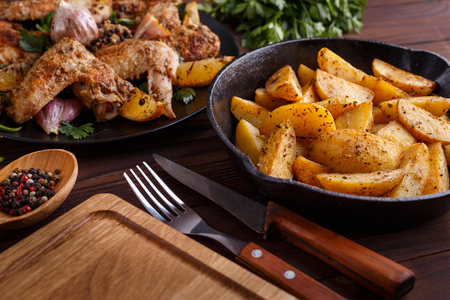 Grilled chicken wings, baked potatoes, herbs and spices on kitchの写真素材