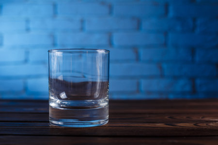 Empty whiskey glass on brick wall background. Alcohol drinks, ba