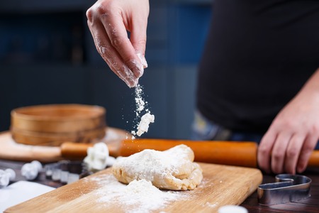 Gingerbread making. Woman sprinkling flour on  gingerbread doughの写真素材