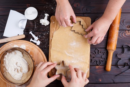 Gingerbread making. Friends cutting cookies of gingerbread doughの写真素材