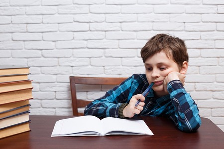 Elementary school kid biting a pen pondering over the task solutの写真素材