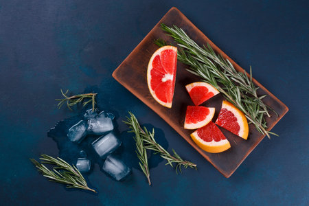 Grapefruit slices with rosemary and melting ice, flat lay on darの写真素材