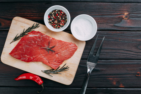 Raw meat, beef steak with rosemary, salt and spices flat lay on