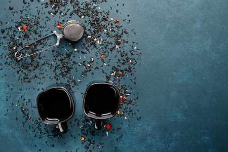 Two cups of black tea with tea stainer and sprinkled tea leavesの写真素材