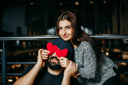 Joyful couple.Young woman covering her boyfriends eyes with redの写真素材
