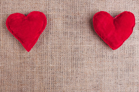 Valentines Day background with two red fabric hearts on sackclot