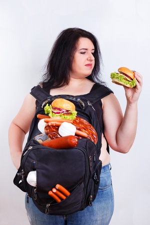 Obese fat young woman with a great backpack full of junk food onの写真素材