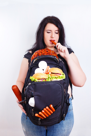 Obese fat young woman with a great backpack full of junk food onの写真素材