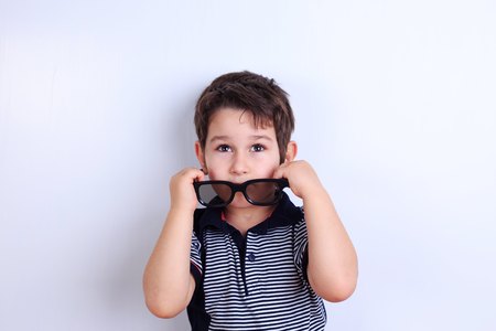 Lovely little boy putting off sunglasses, studio shoot on white.の写真素材