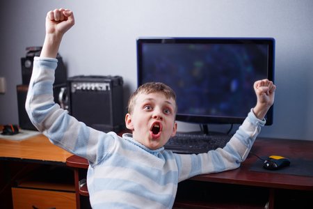 Win the game. Happy jubilant boy playing computer game in his roの写真素材