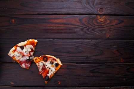 Two slices of pizza on dark wooden table, flat lay, copy spaceの写真素材