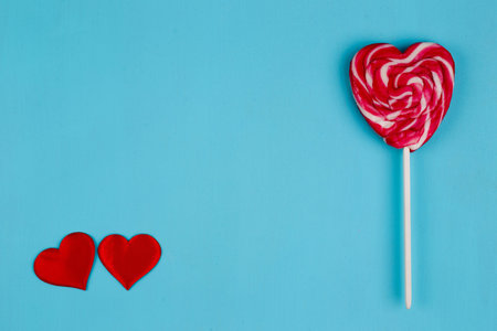 Two red fabric hearts and sweet bright lollipop heart on blue ba