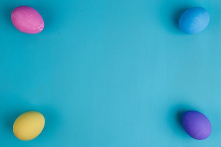 Multicolored Easter eggs on blue background, flat lay with copyの写真素材