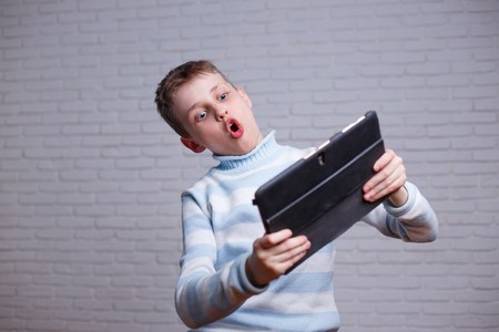 Boy engrossed in playing online game on his tablet. Gadget, inteの写真素材