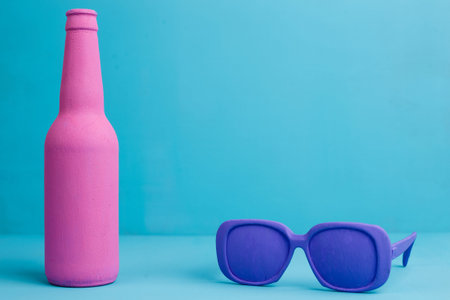 Pink bottle and violet retro style sunglasses on blue background