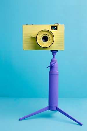 Bright retro vintage camera on tripod on blue background, closeの写真素材