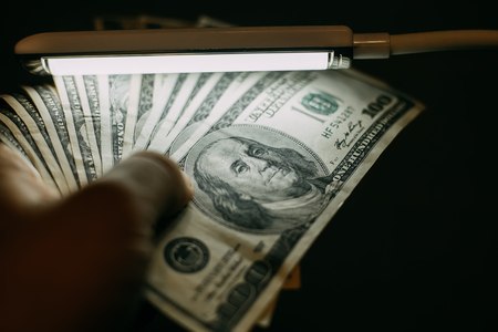 Man hand with a stack of hundred US dollars bills over banknoteの写真素材