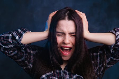 Shouting,screaming young woman, suffering from headache, studioの写真素材