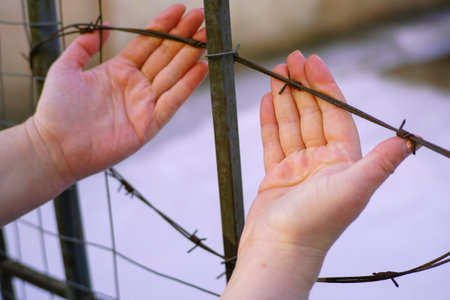 Woman hands and barbed wire. Refugee, prison, captivity conceptの写真素材